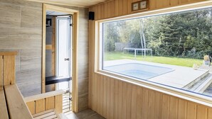 A wooden interior with a large window overlooking a backyard. - 4 Star Holiday Home in Vaeggerlose (Vaeggerlose)