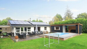 A modern house with a solar panel roof, a swimming pool, and a patio area with outdoor furniture. - 4 Star Holiday Home in Vaeggerlose (Vaeggerlose)
