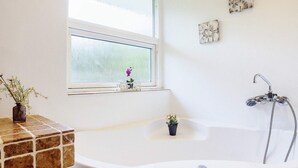 A bathroom with a bathtub, a window, and a shower. - 4 Star Holiday Home in Vaeggerlose (Vaeggerlose)