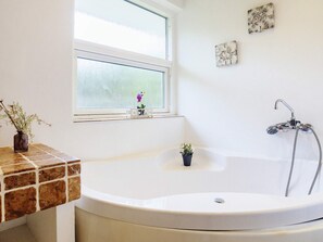 Une salle de bain avec une baignoire, une fenêtre et une douche.