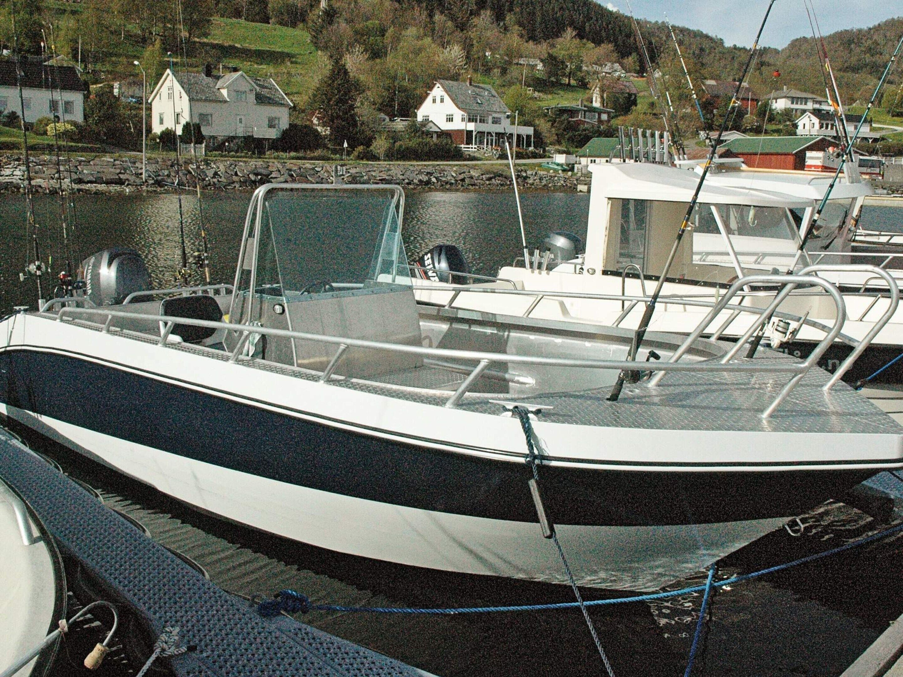 A boat docked at a marina with a view of houses in the background.