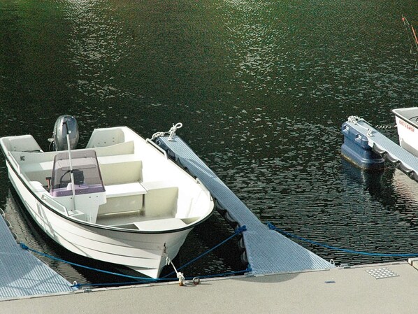 Un petit bateau à moteur blanc était amarré à un quai. Il avait un pont plat et une cabine dotée de fenêtres.