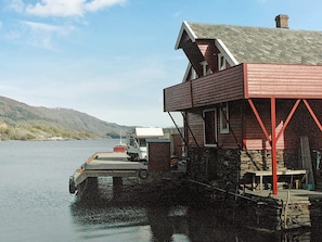 A cabin with a dock extending into a lake, surrounded by hills. - 4 Star Holiday Home in Sorbovag (Hyllestad)
