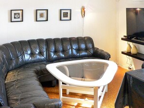 A black leather sofa, a white coffee table, and a flat-screen TV on a stand. - 4 Star Holiday Home in Sorbovag (Hyllestad)
