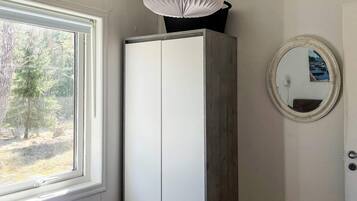Et soveværelse med et vindue, en garderobe og et spejl på væggen.
