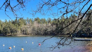 A lake with floating buoys, a dock, and a forested shoreline.