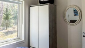 Ein Schlafzimmer mit Fenster, Schrank und Spiegel an der Wand.