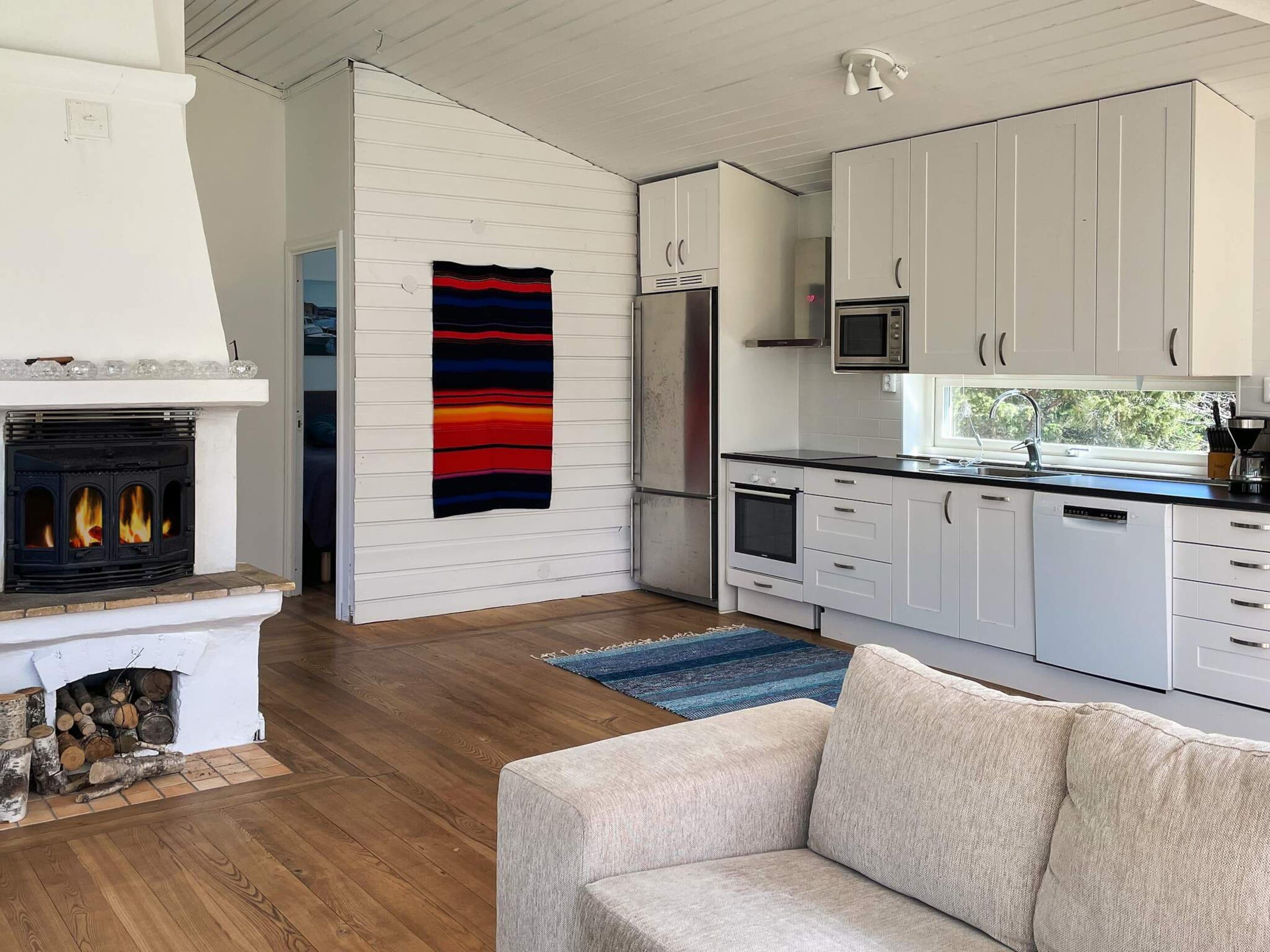 A modern kitchen with white cabinets, a built-in microwave, and a fireplace with logs.