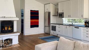 A modern kitchen with white cabinets, a built-in microwave, and a fireplace with logs.