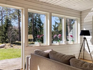 A room with a sofa, a lamp, and a window with a view of trees and a lawn. - 3 Person Holiday Home in Norrtalje (Norrtälje)