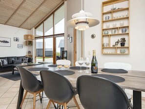 A modern dining area with a wooden table, black chairs, and a bottle of champagne.
