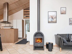 A modern living room with a fireplace, a sofa, and a kitchen area with wooden cabinets.