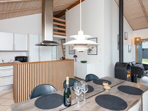 A modern kitchen with a wooden island, a dining area with a table set for four, and a built-in wood stove.