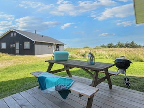 A picnic setup with a table, a blanket, a lantern, and a grill.