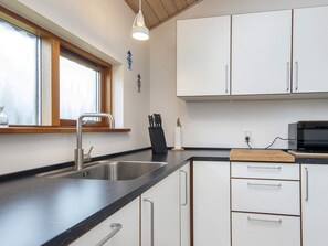 A kitchen with a stainless steel sink, a microwave, and white cabinets.
