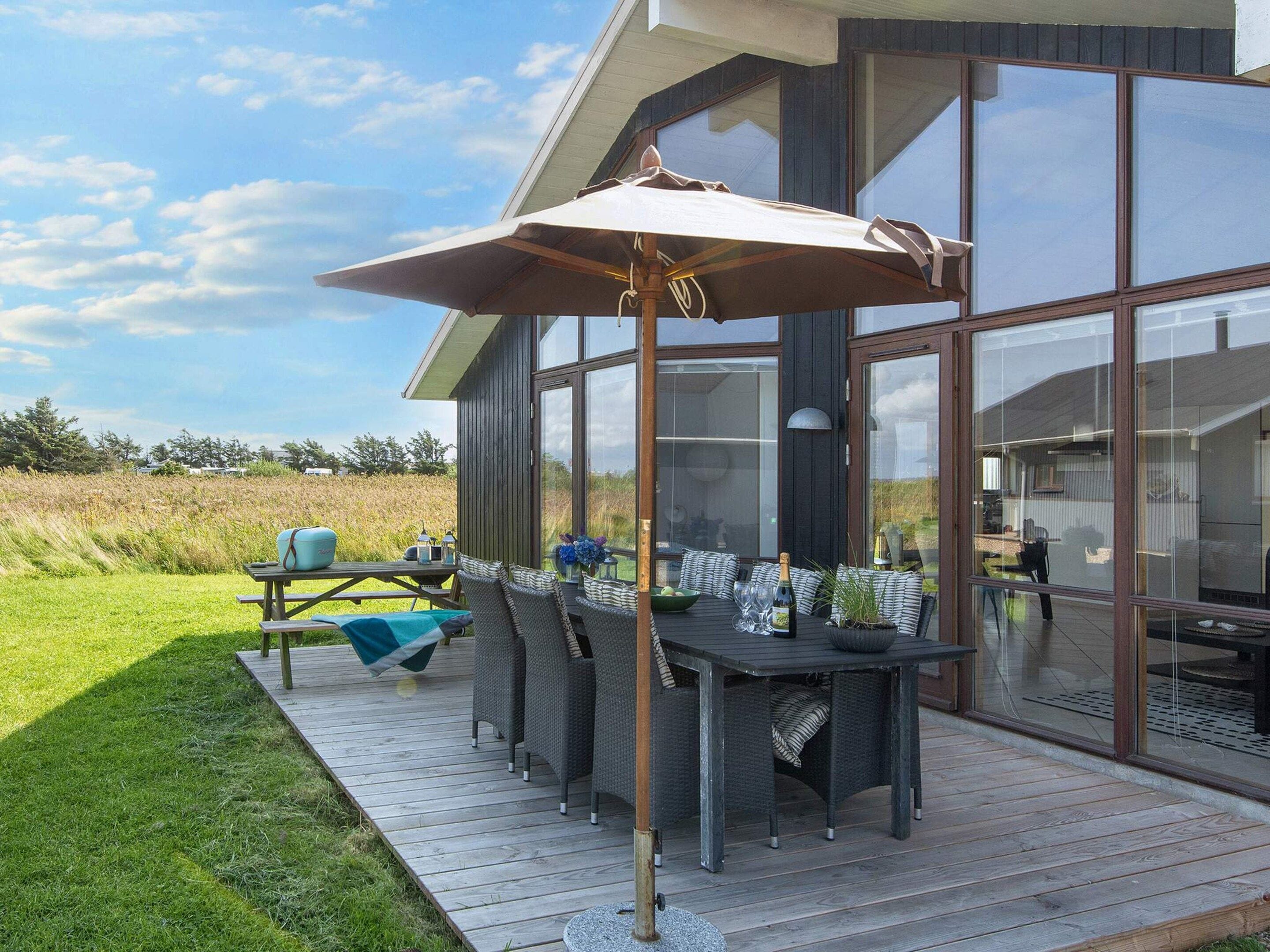 A modern outdoor dining area with a table, chairs, and a large umbrella.