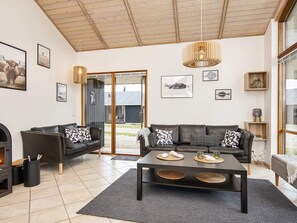 A modern living room with a fireplace, a sofa set, a coffee table, and a large window. - 7 Person Holiday Home in Ulfborg (Ulfborg)