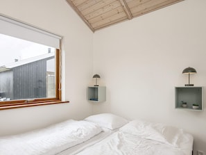 A bedroom with a single bed, a window, and two wall-mounted lamps.