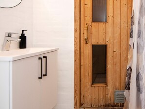 A bathroom with a wooden door, a white sink with a soap dispenser, and a mirror above the sink. - Tranquil Holiday Home in Ulfborg With Sauna (Ulfborg)