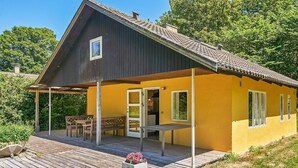 A two-story house with a wooden deck and a covered patio area. - 6 Person Holiday Home in Aakirkeby (Akirkeby)
