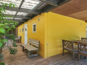 A yellow building with a wooden deck, benches, and a covered area with a roof. - 6 Person Holiday Home in Aakirkeby (Akirkeby)
