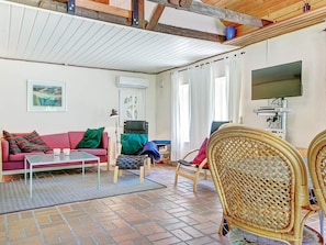 A living room with a sofa, a coffee table, a wicker chair, a television, and a medical device on a stand.