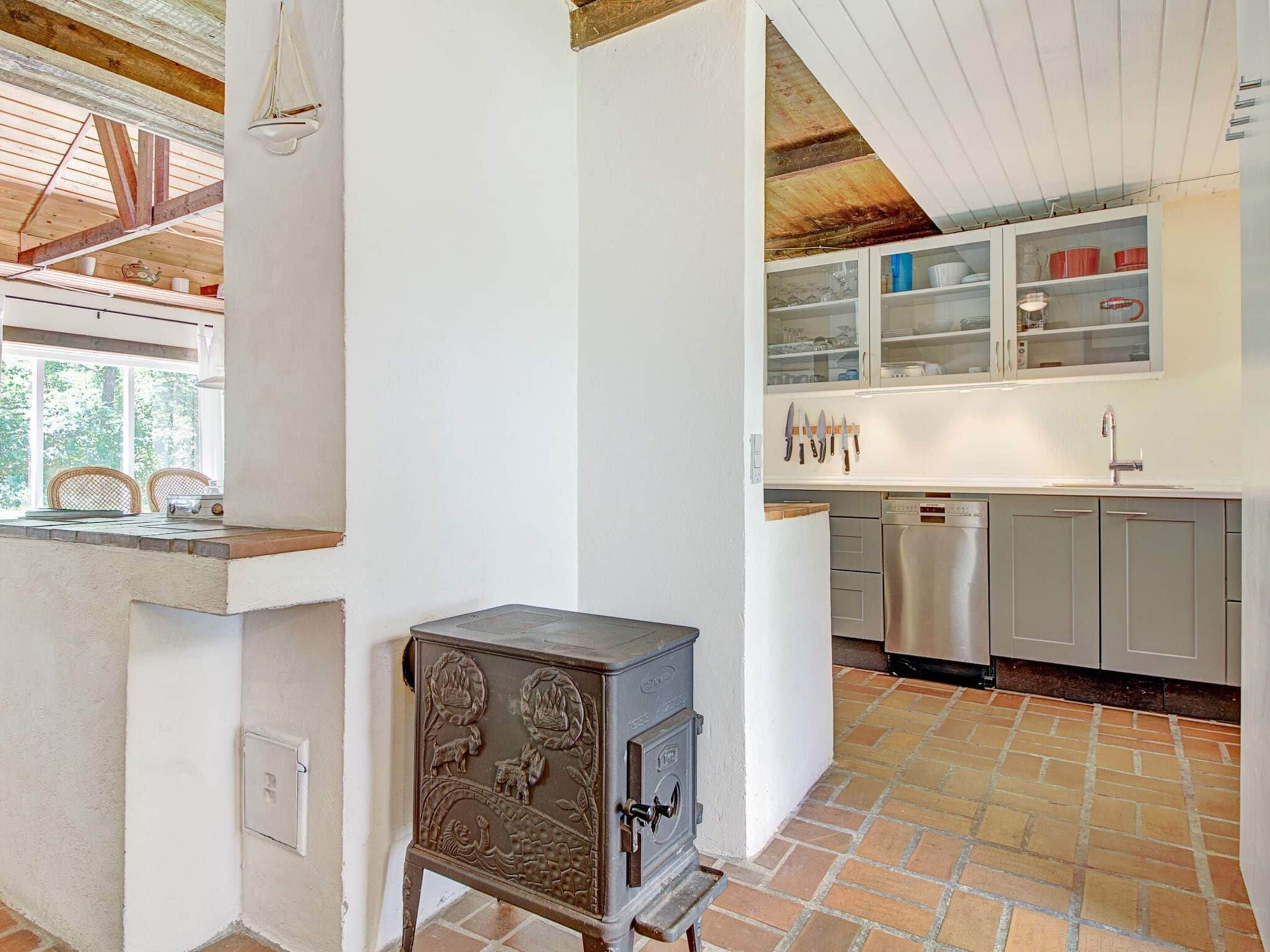 A kitchen with a rustic stove, modern appliances, and a view of the outdoors.