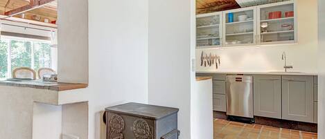 A kitchen with a rustic stove, modern appliances, and a view of the outdoors.