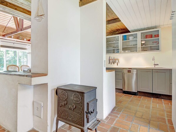 A kitchen with a rustic stove, modern appliances, and a view of the outdoors.
