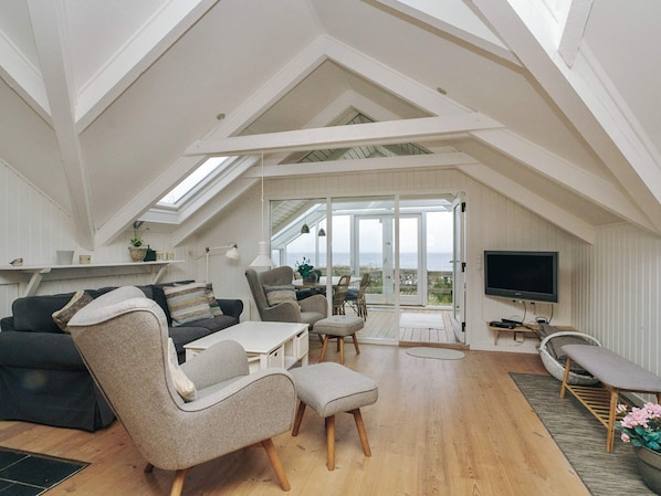 Une piĂšce de style loft avec un haut plafond, une grande fenĂȘtre, un tĂ©lĂ©viseur Ă Ă©cran plat et un coin repas.