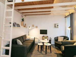 A modern living room with a sofa, two armchairs, a coffee table, and a TV.