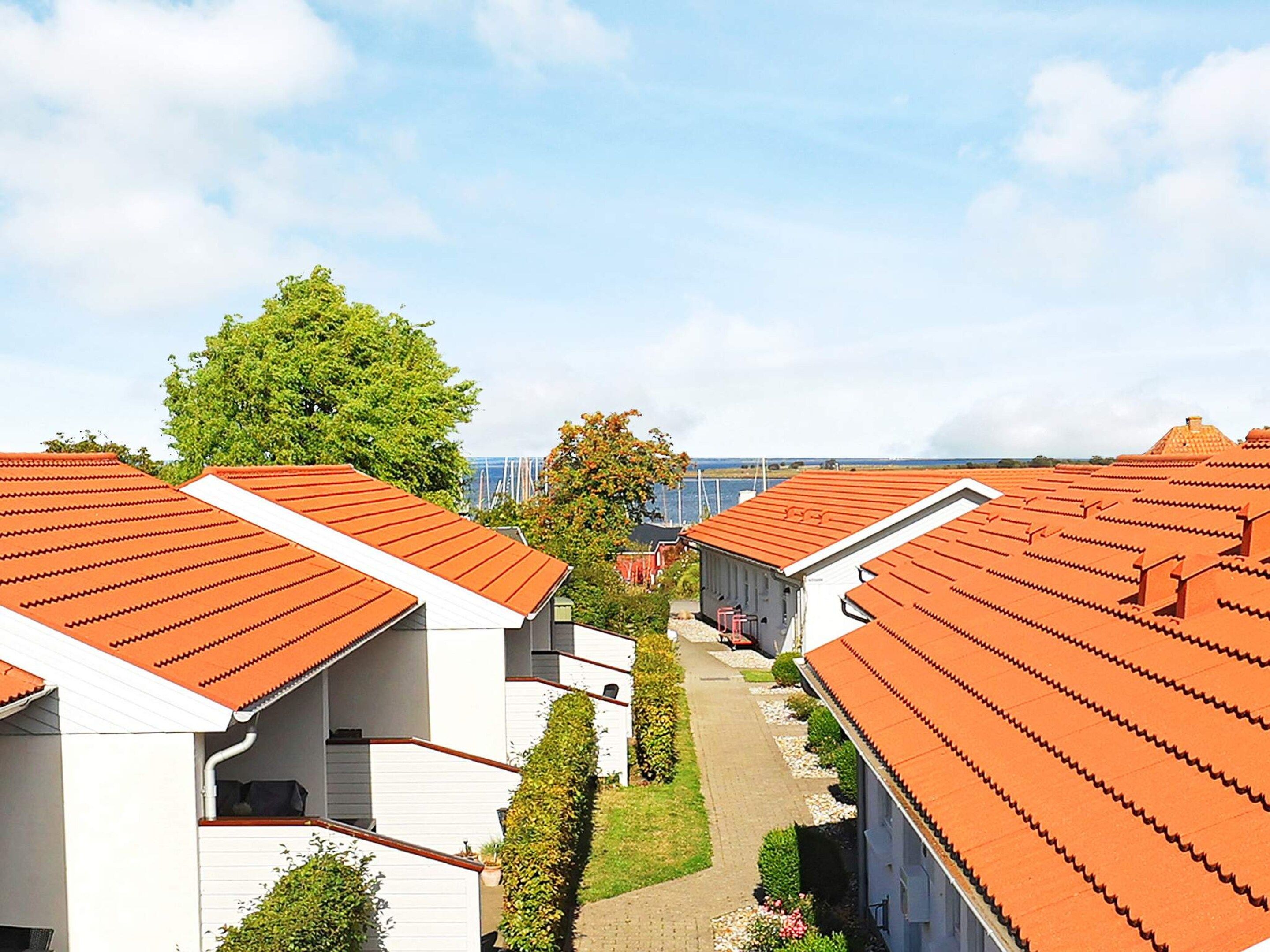 A row of white buildings with orange roofs, arranged in a linear fashion with a pathway between them.