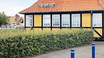 A building with a yellow facade and black trim, featuring a sign that reads "Fyns Amts Avis!"