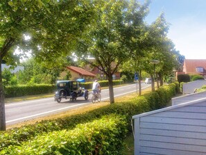 A street scene with a vintage car, a cyclist, and a residential area with houses and greenery. - Cozy Holiday Home in Ã†rÃ¸skÃ¸bing near Harbour (Aeroskobing)
