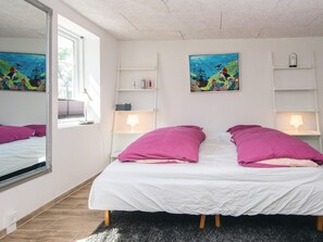 Une chambre à coucher comprenant un lit, deux tables de chevet, un miroir et deux étagères fixées au mur.