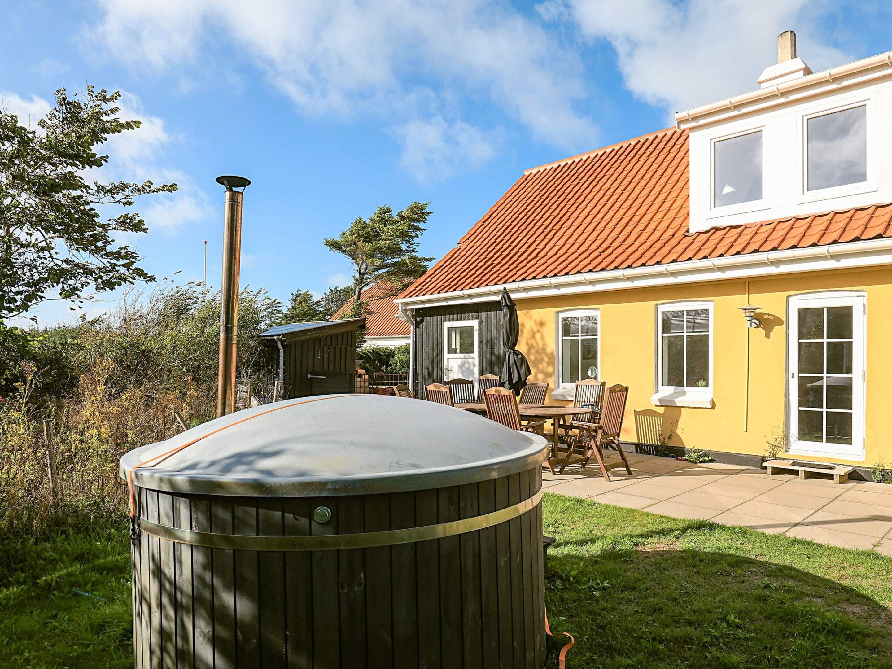 En bolig med terrasse, udendørs møbler og et spabad.