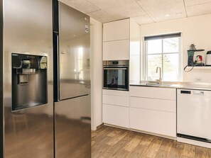 A modern kitchen with stainless steel appliances, a built-in oven, and a water dispenser.