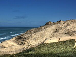 A coastal landscape with a sandy beach and a rocky cliff.