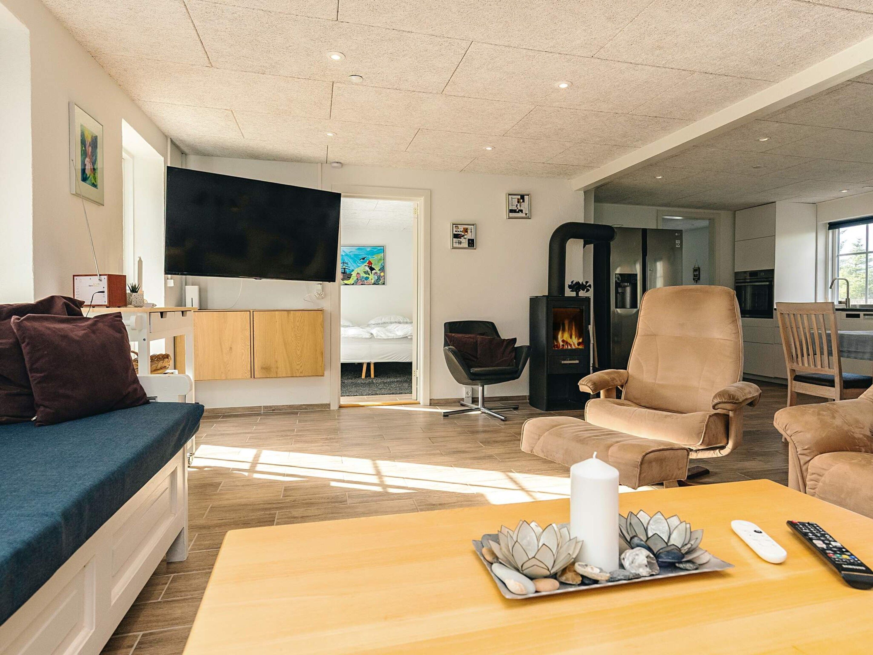 Un salon moderne comprenant un canapé, des fauteuils, un téléviseur, une cheminée et un coin repas.