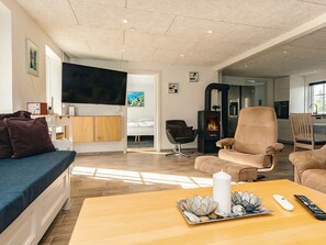 Un salon moderne comprenant un canapé, des fauteuils, un téléviseur, une cheminée et un coin repas.
