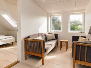 A modern living room with a sofa, two armchairs, a small table, and a skylight. - 4 Star Holiday Home in Lokken (Lokken)
