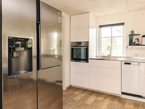 Cozinha moderna com eletrodomésticos de aço inoxidável, forno embutido e dispenser de água.