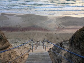 A wooden staircase leading to a beach with a sandy shore and ocean waves. - 4 Star Holiday Home in Lokken (Lokken)