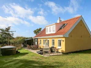 A yellow house with a red roof, a patio with outdoor furniture, and a barbecue grill. - 4 Star Holiday Home in Lokken (Lokken)