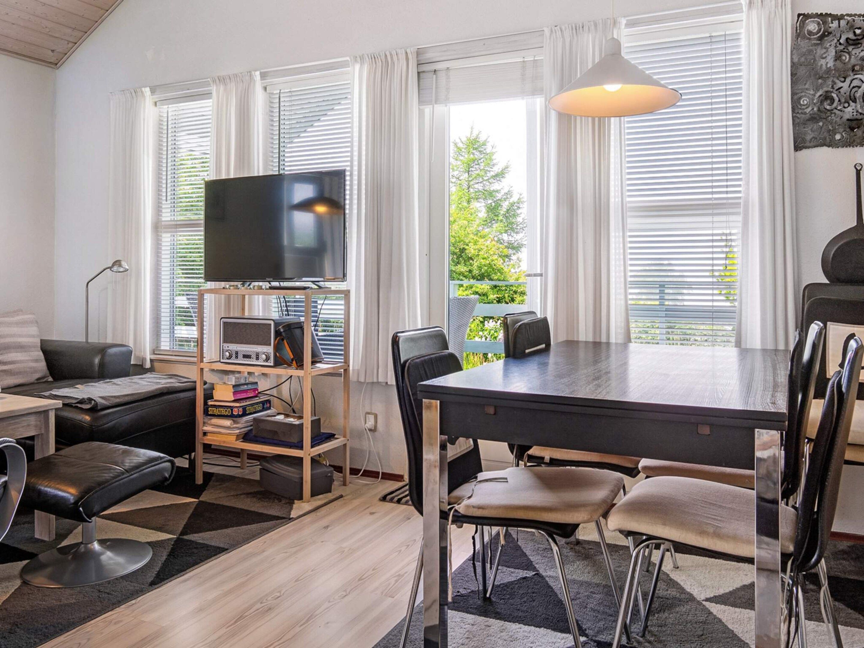 A modern living room with a flat-screen TV, a dining table with chairs, a sofa, and a coffee table.