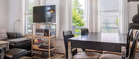 Una sala moderna con un televisor de pantalla plana, una mesa de comedor con sillas, un sofá y una mesa de centro.