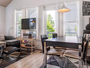 Un salon moderne avec un téléviseur à écran plat, une table à manger avec des chaises, un canapé et une bibliothèque.