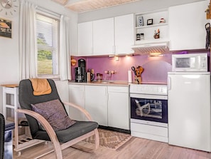 A compact kitchen with white cabinets, a microwave, a stove, and a coffee maker.