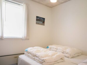 A bedroom with a bed, a window with curtains, and a painting on the wall. - 6 Person Holiday Home in Hasle (Hasle)