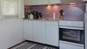 A compact kitchen with white cabinets, a stove, and a microwave. - 6 Person Holiday Home in Hasle (Hasle)